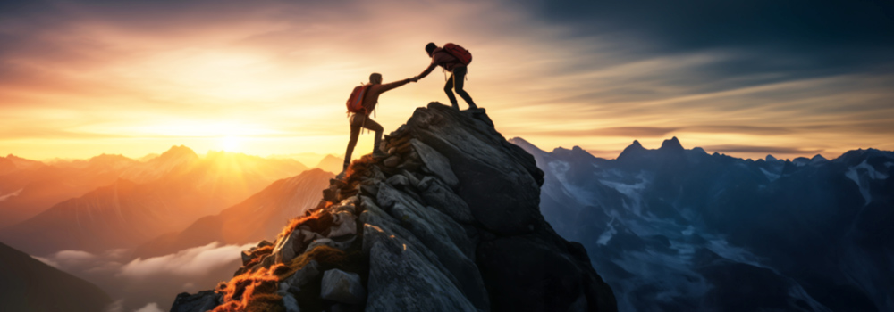 Hiker helping another hiker up a cliff